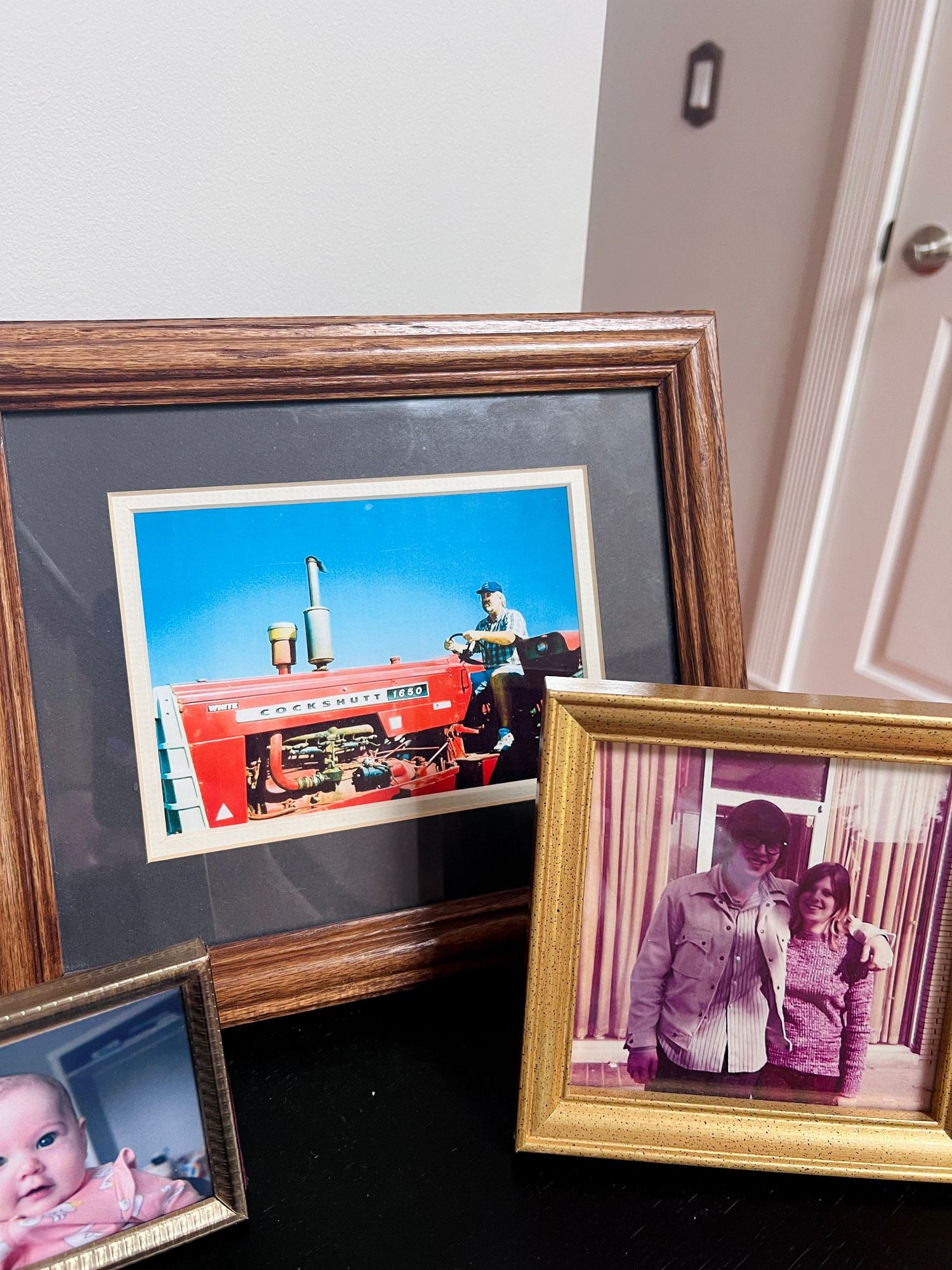Collection of framed family photos displayed on a surface including a vintage couple portrait.