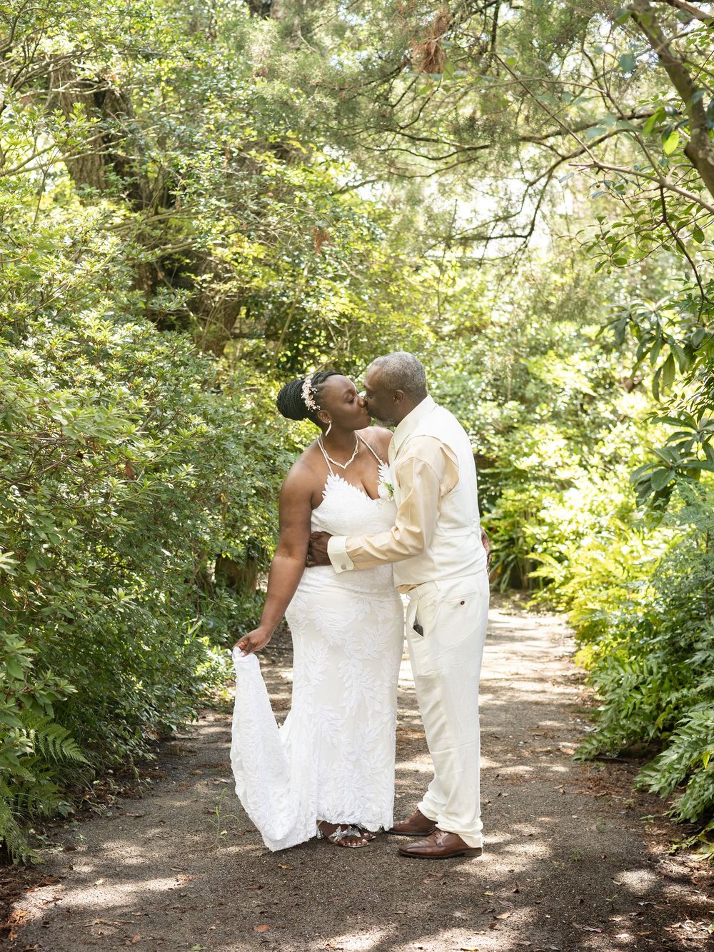 A series of romantic wedding photos taken on a sunlit garden path surrounded by lush greenery.