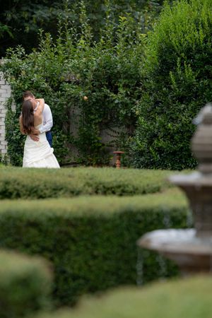 A romantic couple shares an intimate moment in a lush garden setting with green foliage in the background.