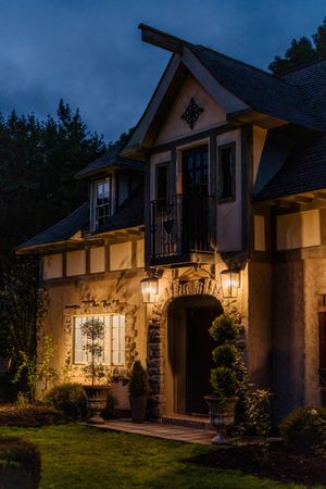 Elegant French country style home exterior with warm lighting at dusk showcases beautiful architectural details and landscaping.