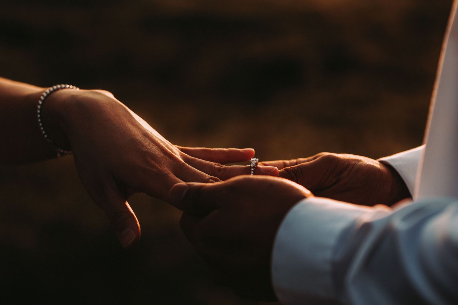 Two hands gently touching in warm golden light symbolizing connection and intimacy in a romantic moment.