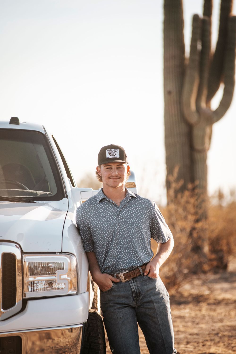 A Ford pickup truck posed next to a towering saguaro cactus in the desert landscape.