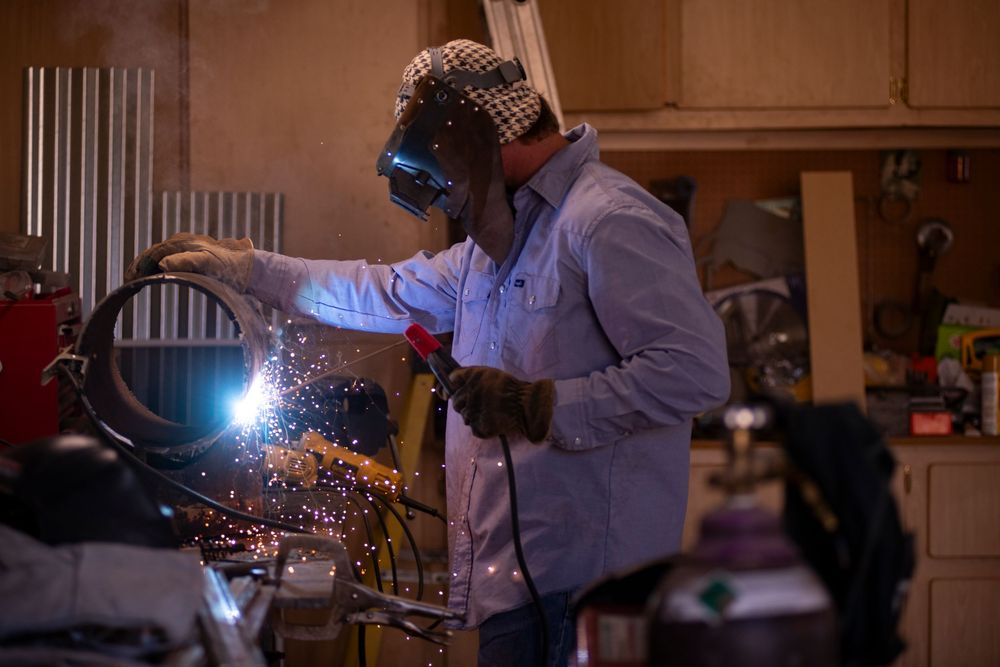 Welder in safety gear creating bright sparks while working on a project in a workshop.