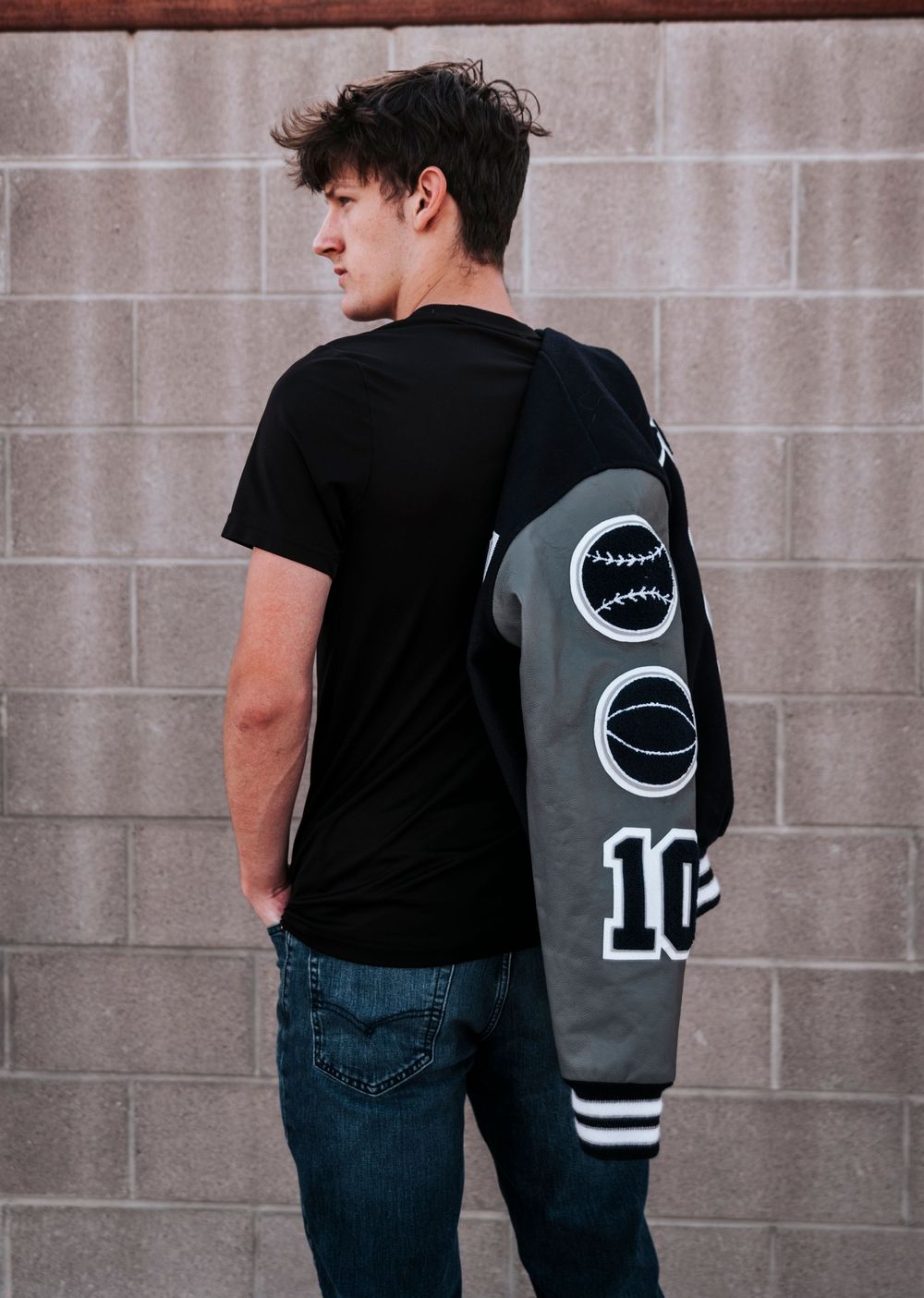 Athletic jacket with graphic designs shown on person against concrete wall.