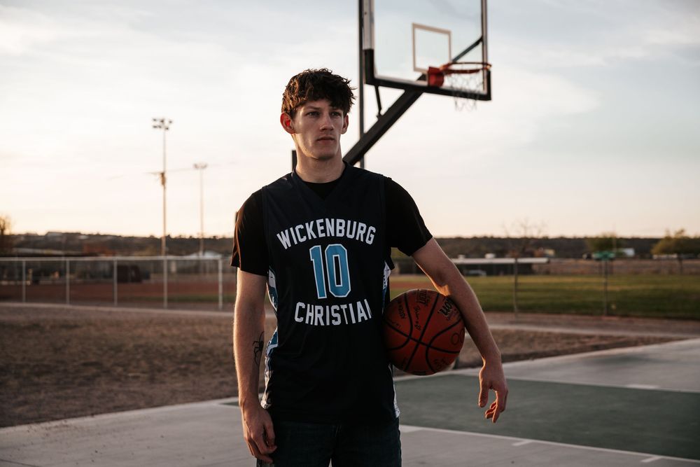 Basketball player in Wickenburg Christian jersey stands on outdoor court.