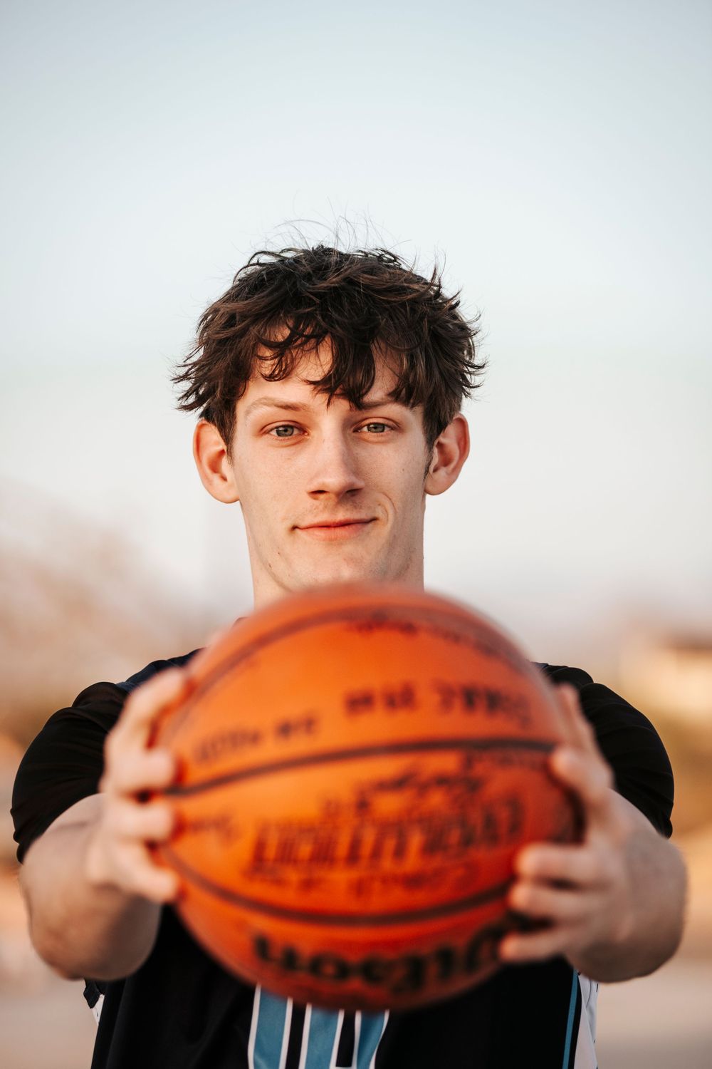 Close up shot of basketball player holding orange ball in front of camera.