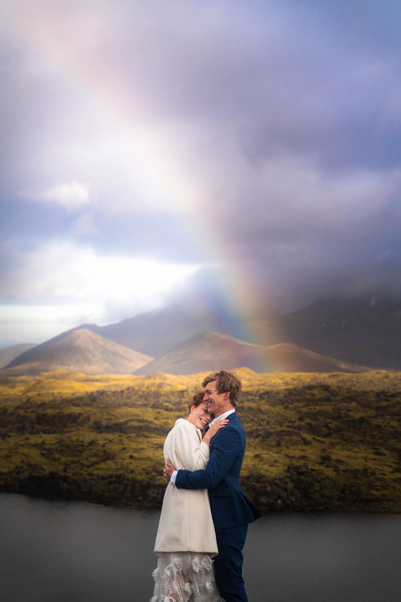 A wedding couple walks along a dramatic mountain landscape with sweeping views.
