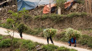 Colorful tents and temporary shelters dot a hillside settlement in a rural mountainous area.