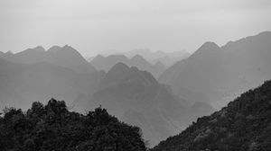 Panoramic mountain landscape with dramatic peaks silhouetted against a misty gray sky.
