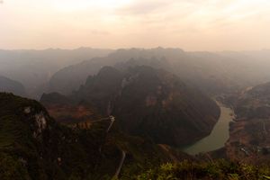 Sunset view of a meandering river valley surrounded by steep mountain ranges.