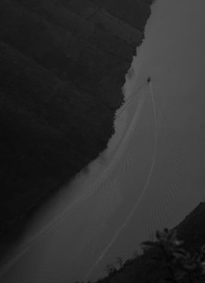 Dark silhouettes of mountain ridges against a dim sky with thin lines visible in the distance.