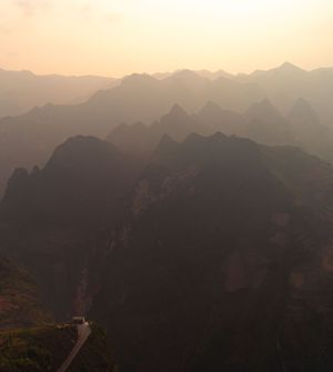 Majestic mountain range silhouetted against a golden sky at dusk with layered peaks extending to the horizon.