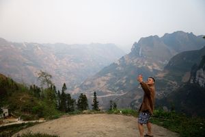Panoramic mountain landscape with dramatic rocky peaks and valleys shrouded in misty clouds.