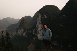 Mountain landscape at sunset with rocky cliffs and deep valleys in the background.