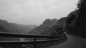 Black and white panoramic view of a winding mountain road with misty valleys.
