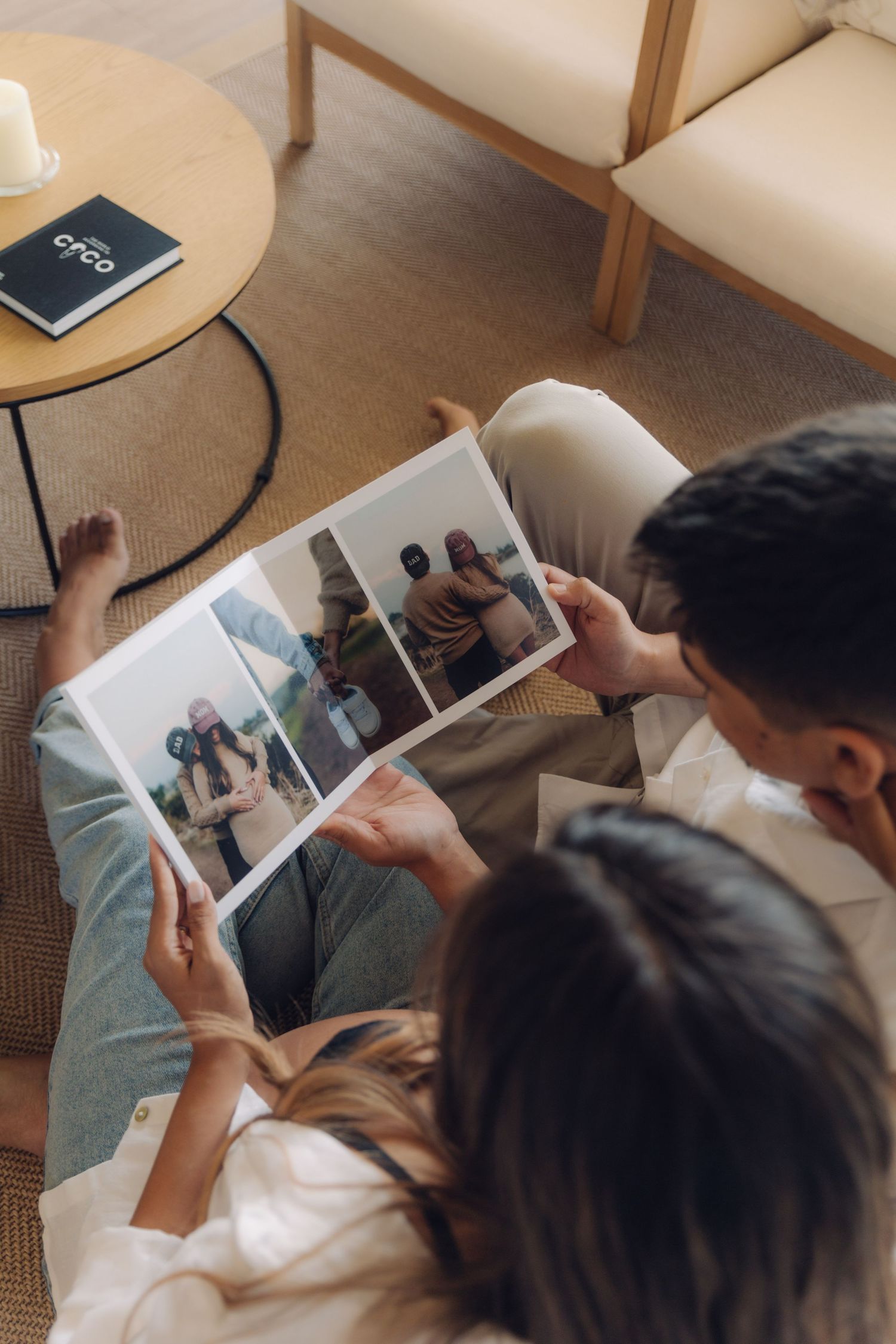 Overhead view of couple looking at printed family photos together while seated on floor.