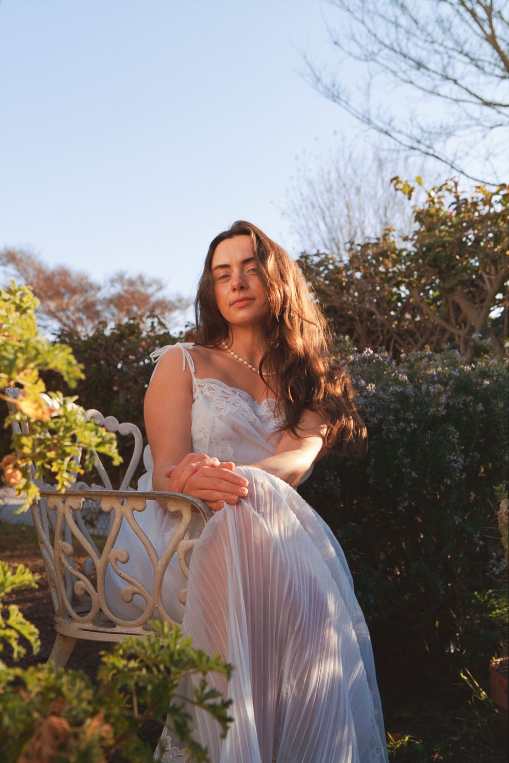 Romantic garden scene with vintage white dress and ornate chair details.