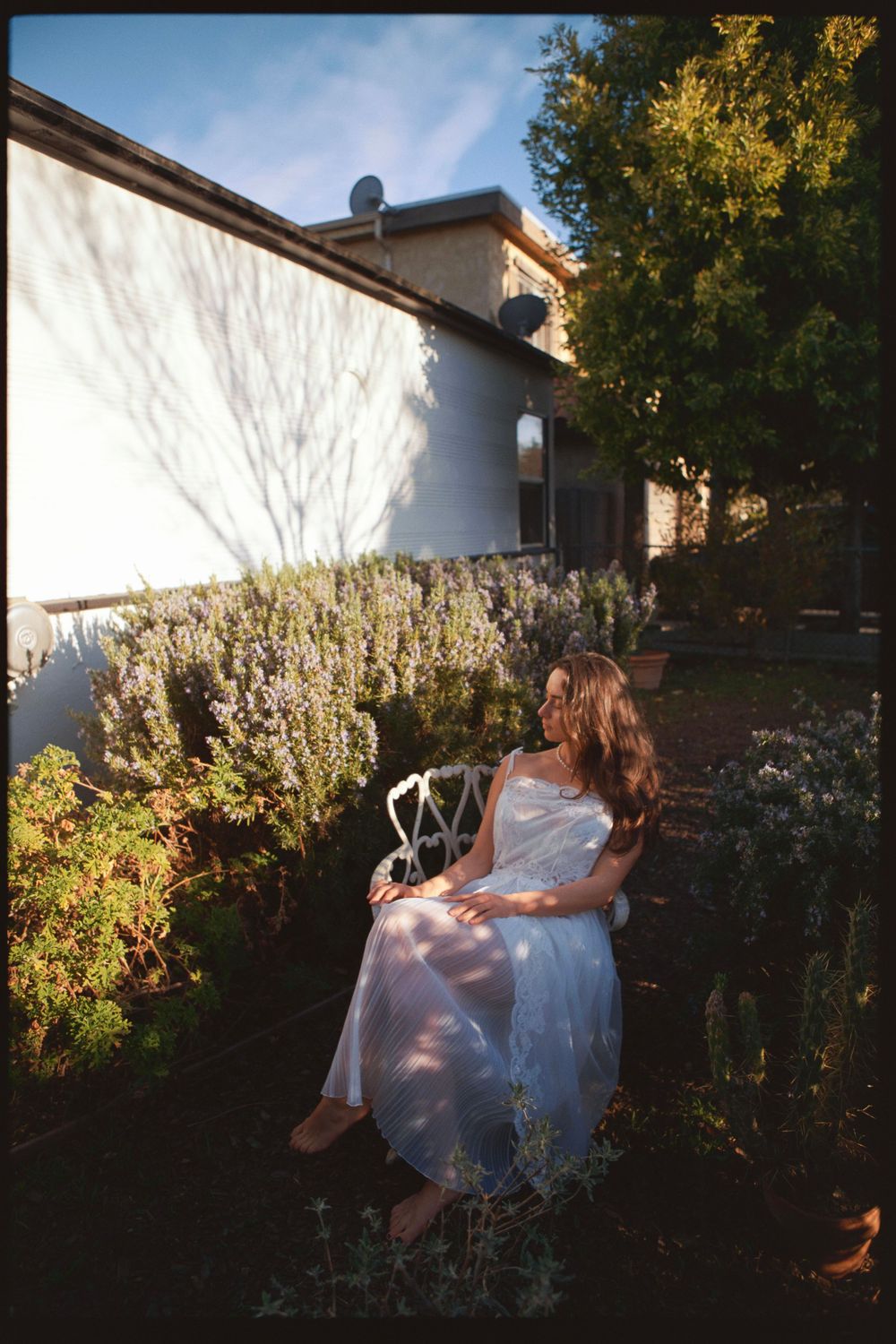 Garden photoshoot featuring delicate white dress and natural backyard setting.