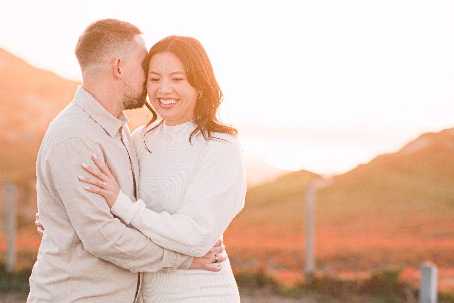 A couple embraces during golden hour sunset in on the Monterey Sandunes.