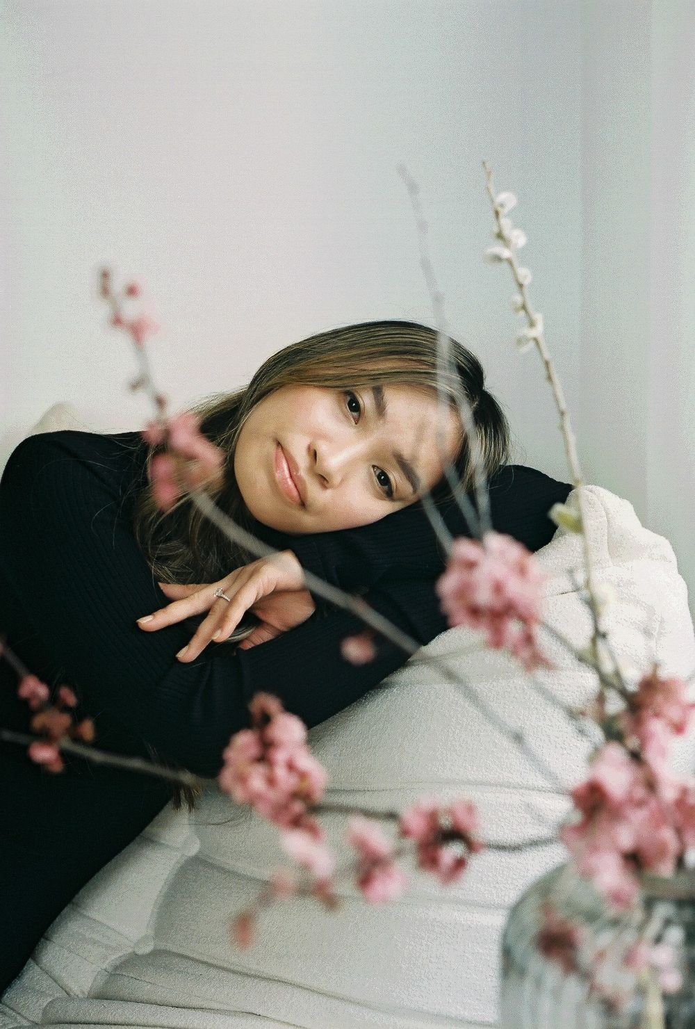 Person resting on couch with cherry blossoms in foreground creating dreamy atmosphere.
