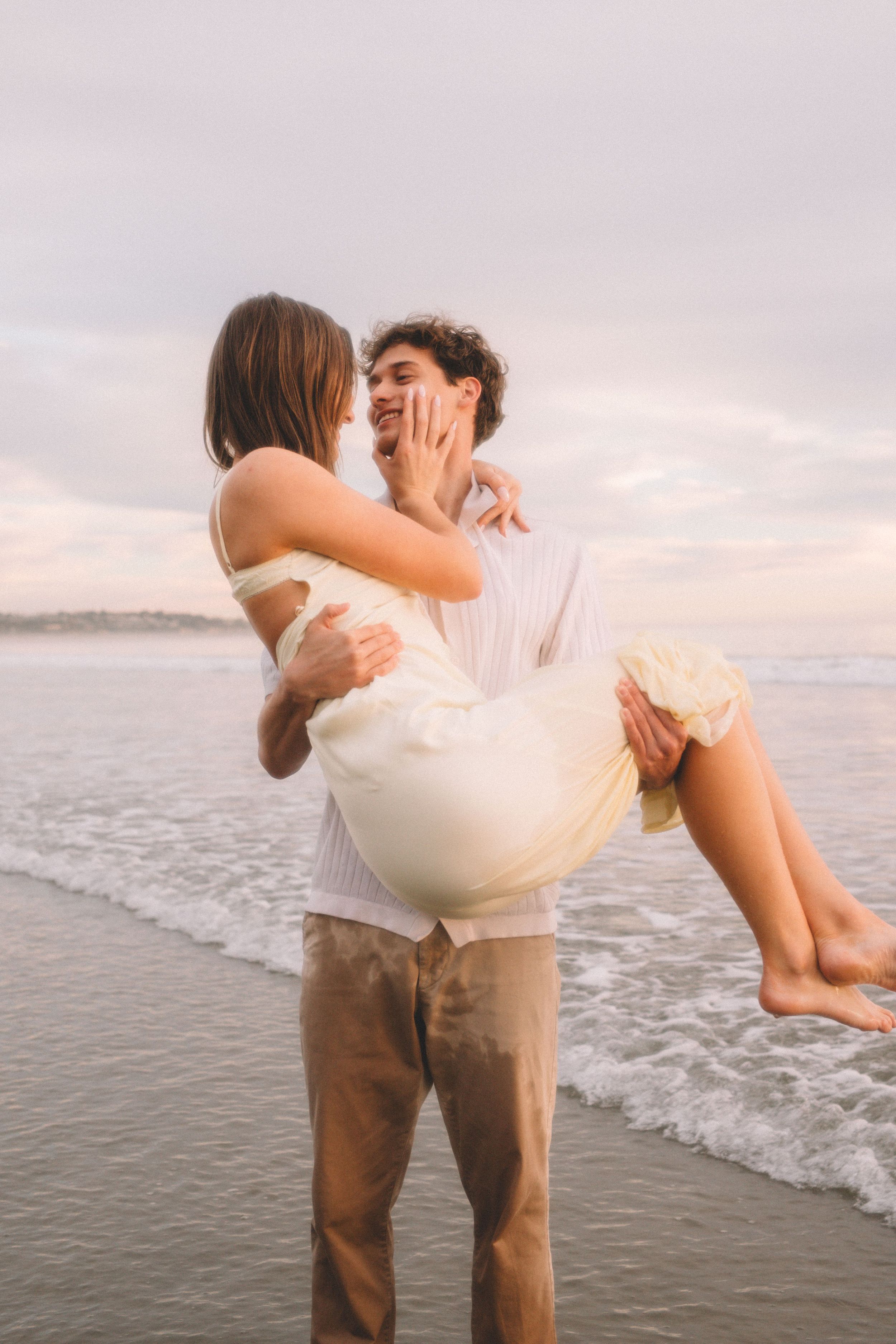 Couple shares playful moment on beach shoreline during golden hour.