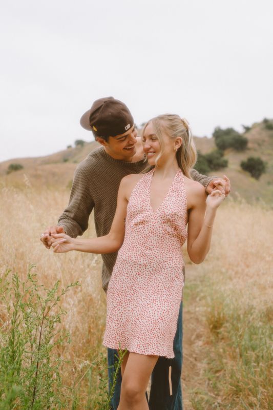 Couple sharing intimate moment in sunny meadow with golden grass.