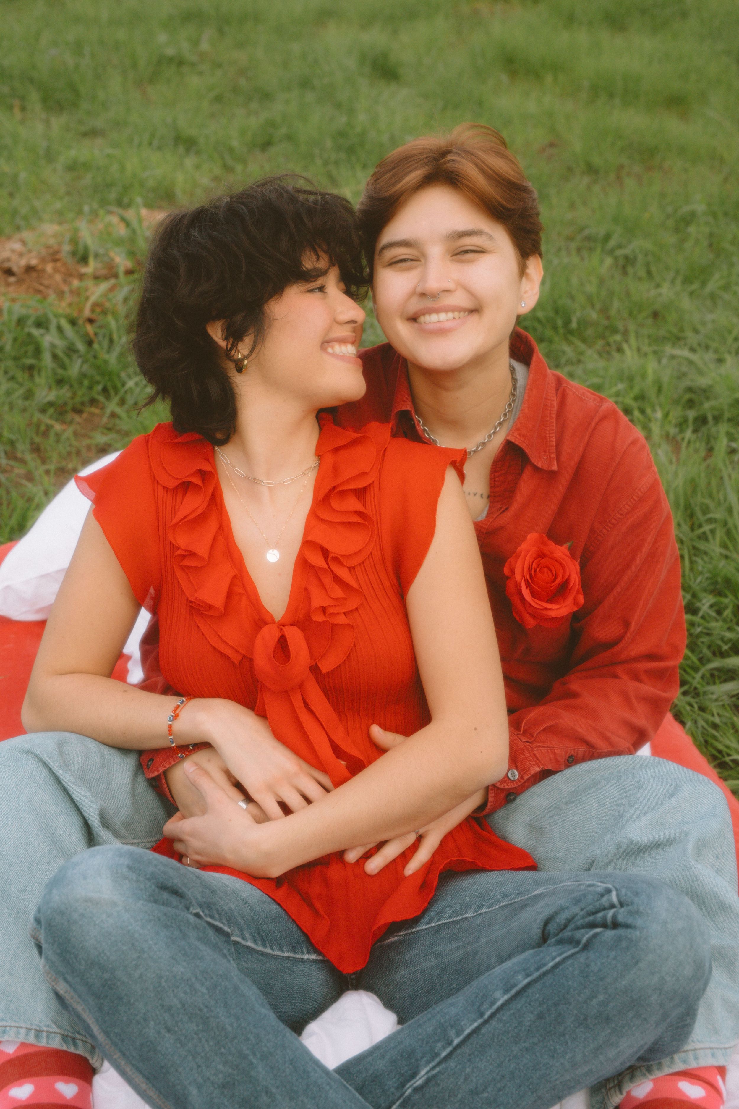 Couple in matching red outfits sharing tender moment on grass.