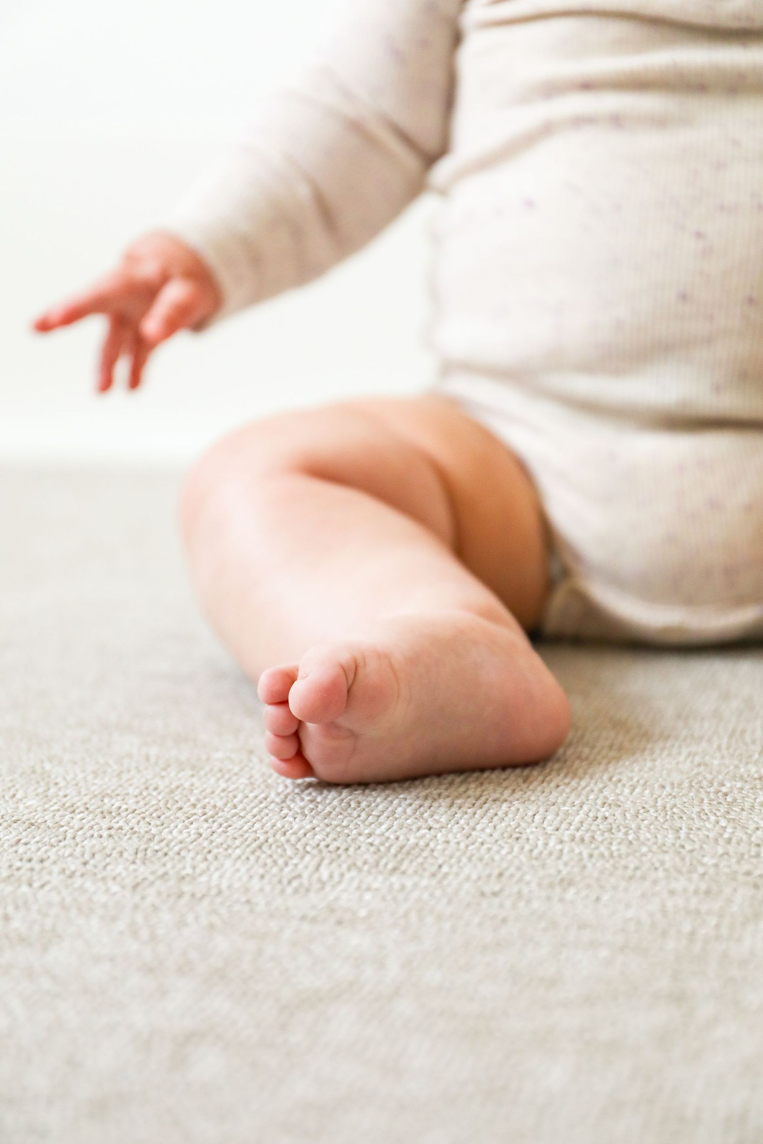 Close-up view of a baby's tiny bare foot against a light gray textured carpet, during Sitter photoshoot based in Nottingham