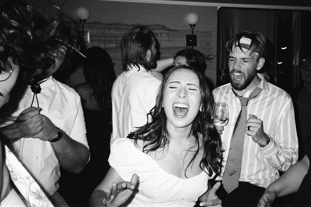 Dynamic black and white shot of people celebrating and dancing at a festive event.