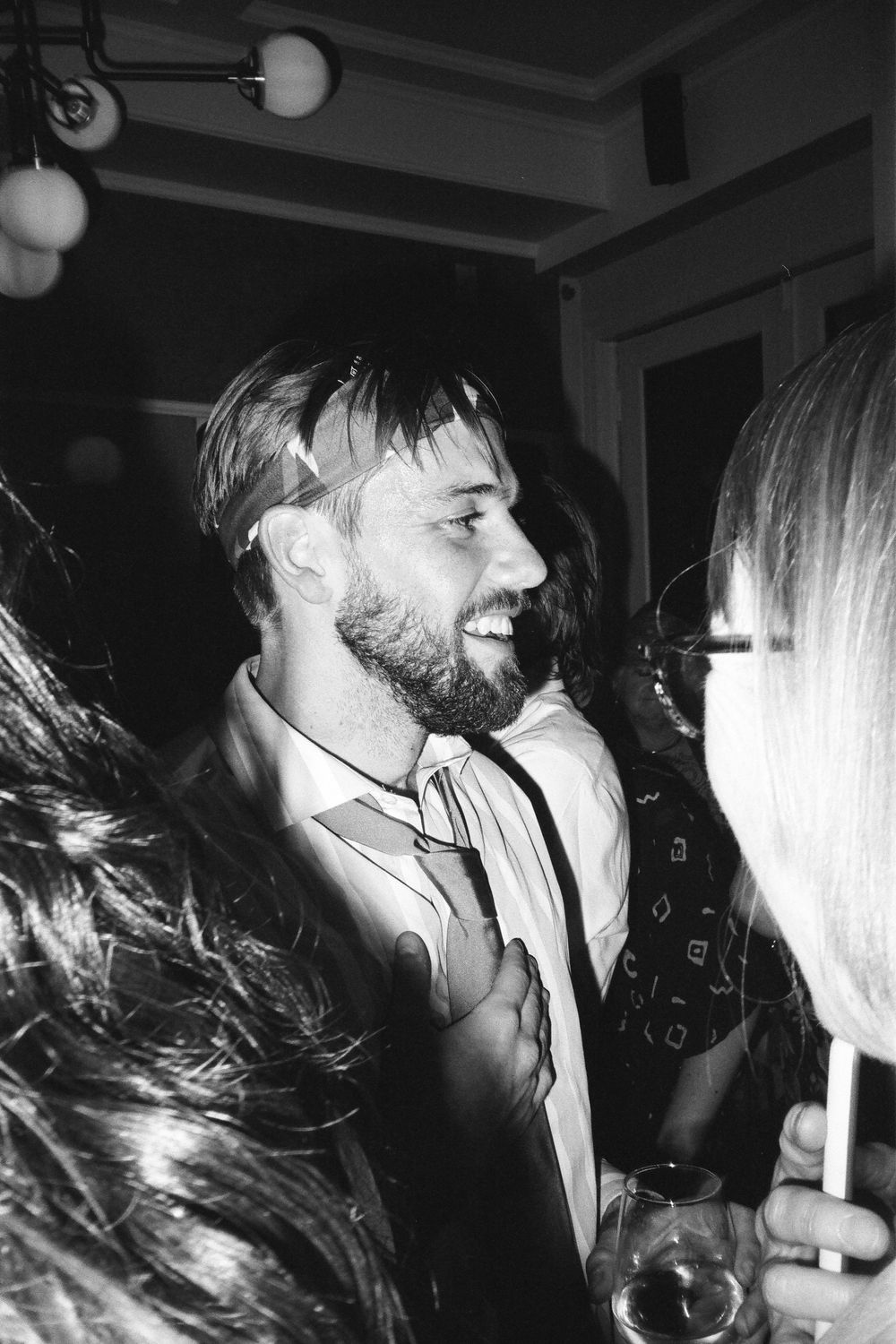 Black and white photograph capturing intimate moments between dancers at a celebration.