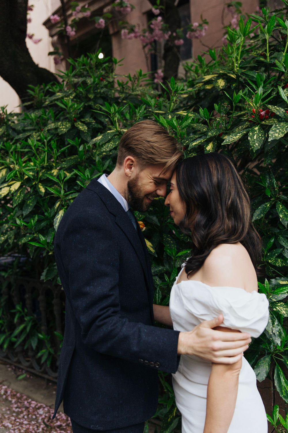 A romantic moment between newlyweds in front of lush green foliage.