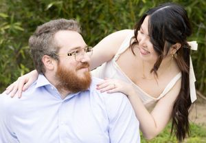 Two people share a joyful moment together outdoors with a green garden backdrop.