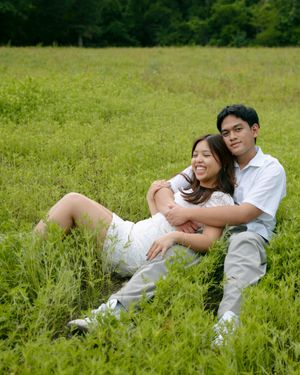 A couple in white clothing relaxes together on a grassy meadow on a sunny summer day.