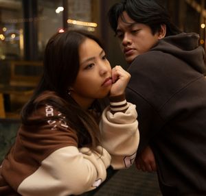 Two people in winter clothes share an intimate moment in a dimly lit setting with warm lighting effects.