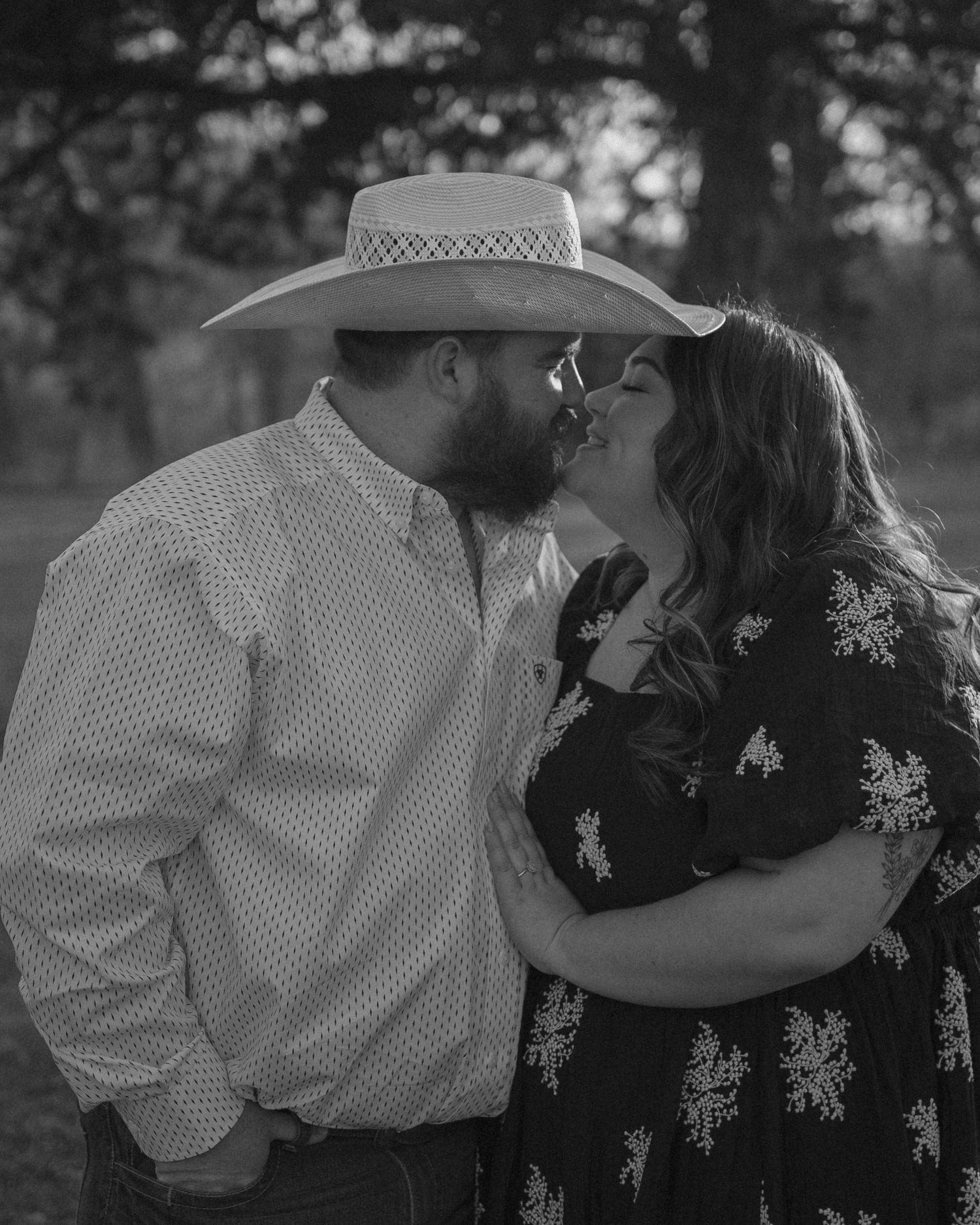 A romantic black and white photograph of a couple sharing an intimate kiss in a rustic country setting.