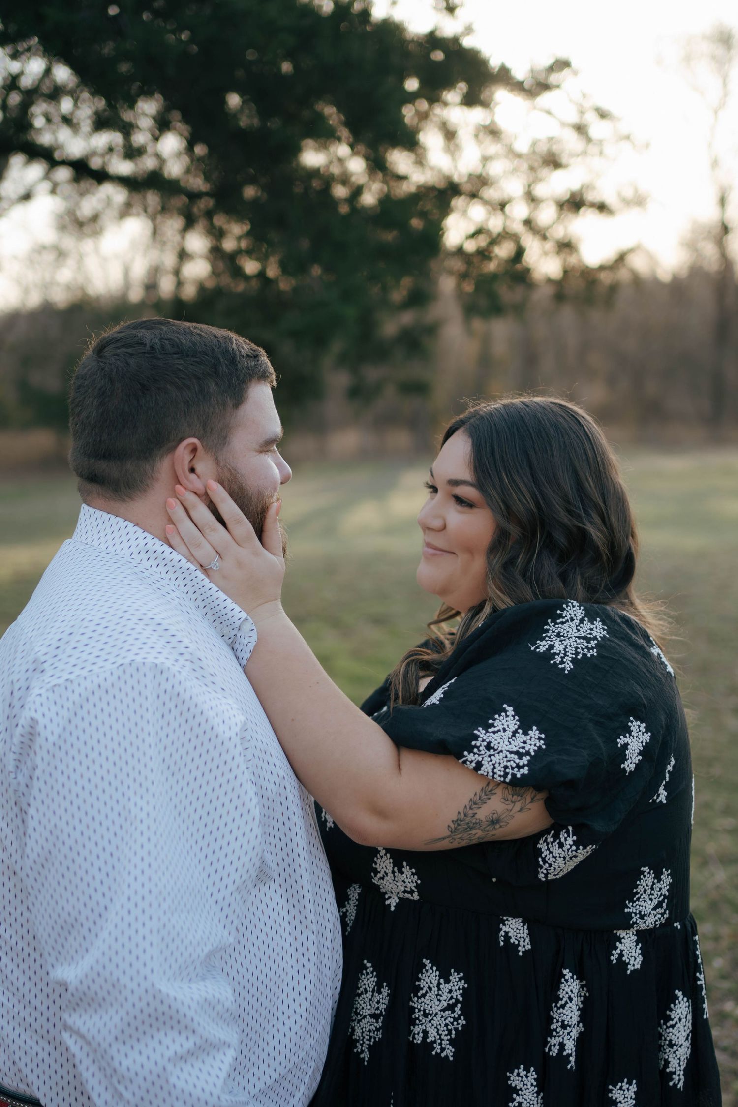 A tender outdoor portrait of a couple sharing an intimate moment at sunset in a natural setting.