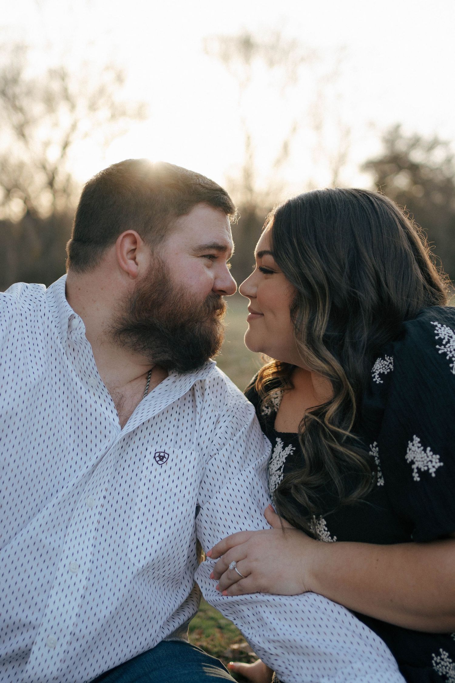 A romantic couple shares an intimate moment at sunset, with sunlight glowing behind them.