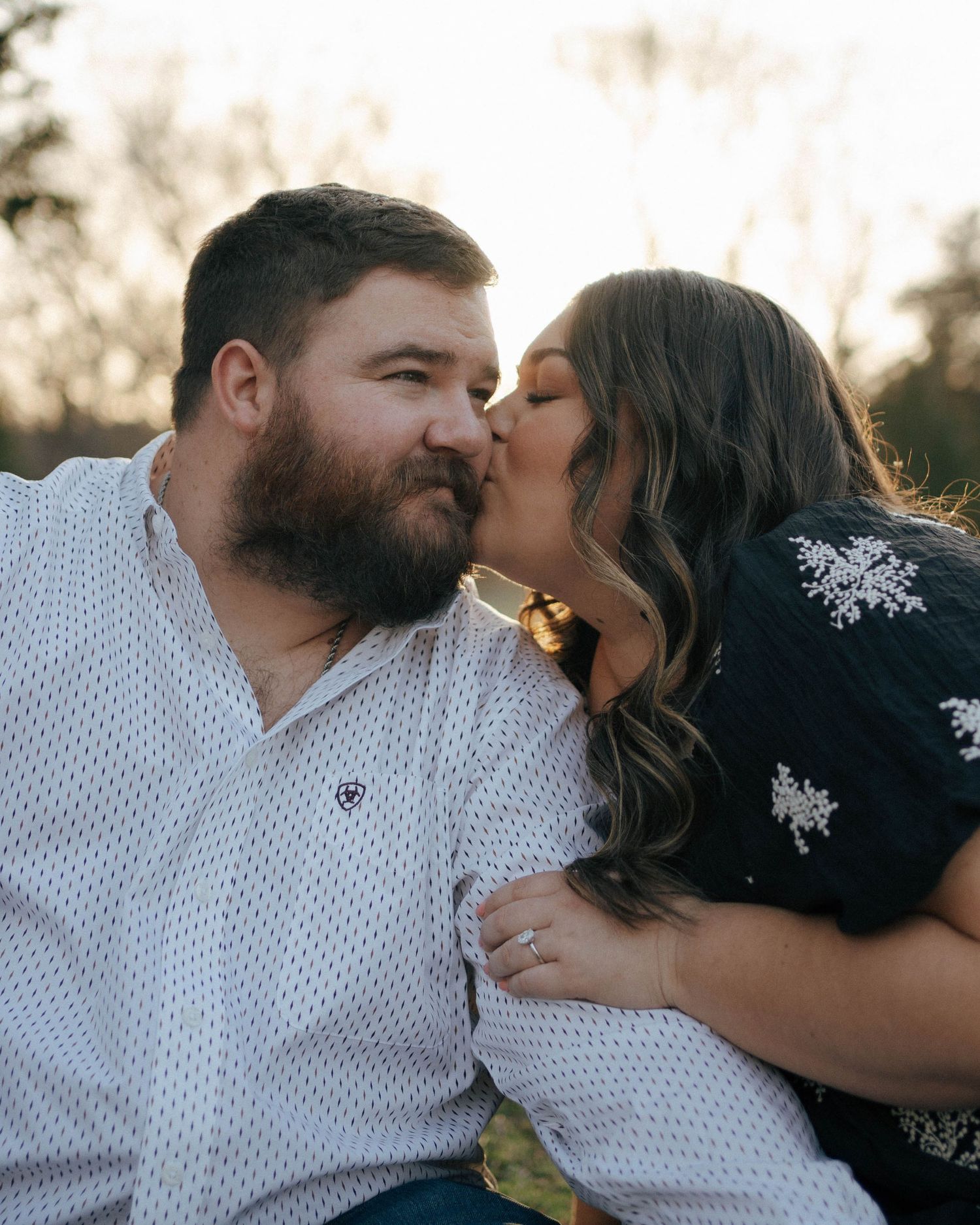An intimate couple gazes at each other lovingly while bathed in warm golden hour light.