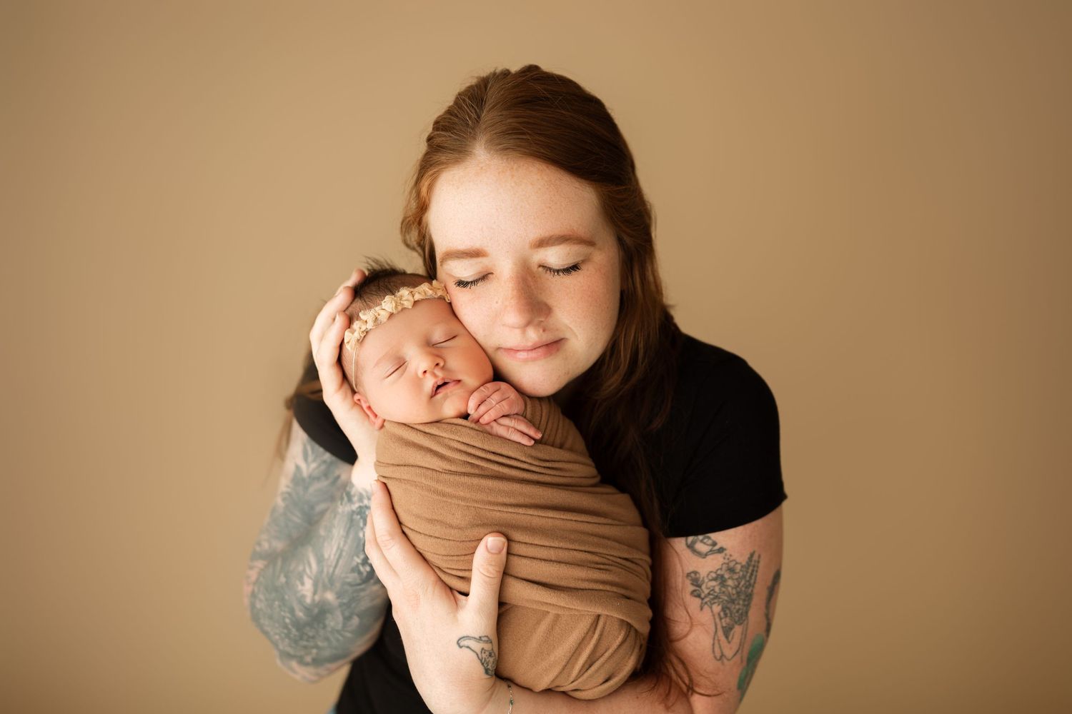 Warm-toned studio portraits capture tender moments with wrapped newborn.