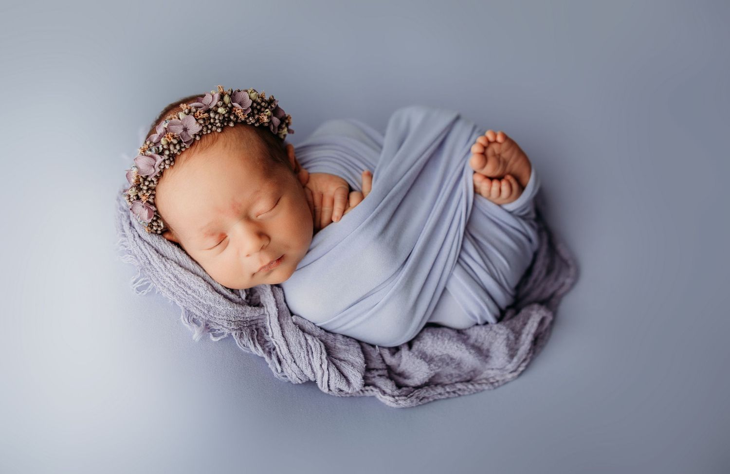 A series of artistic newborn portraits featuring soft gray wraps against a neutral backdrop.