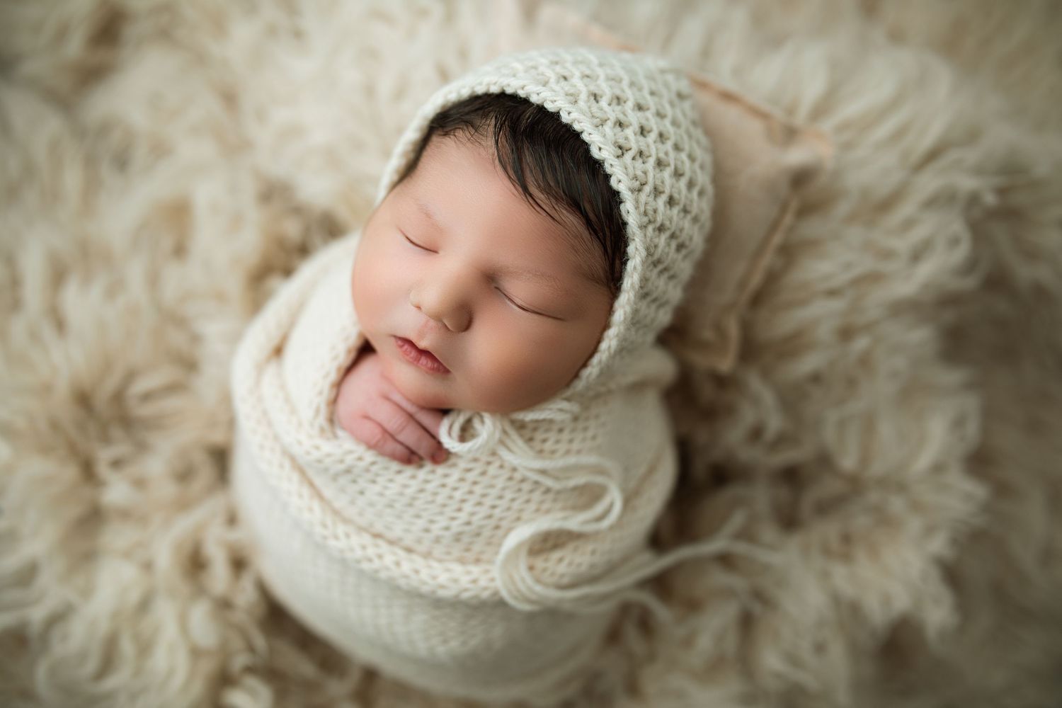 Artistic newborn portrait series with cream colored knit bonnets against a textured backdrop.