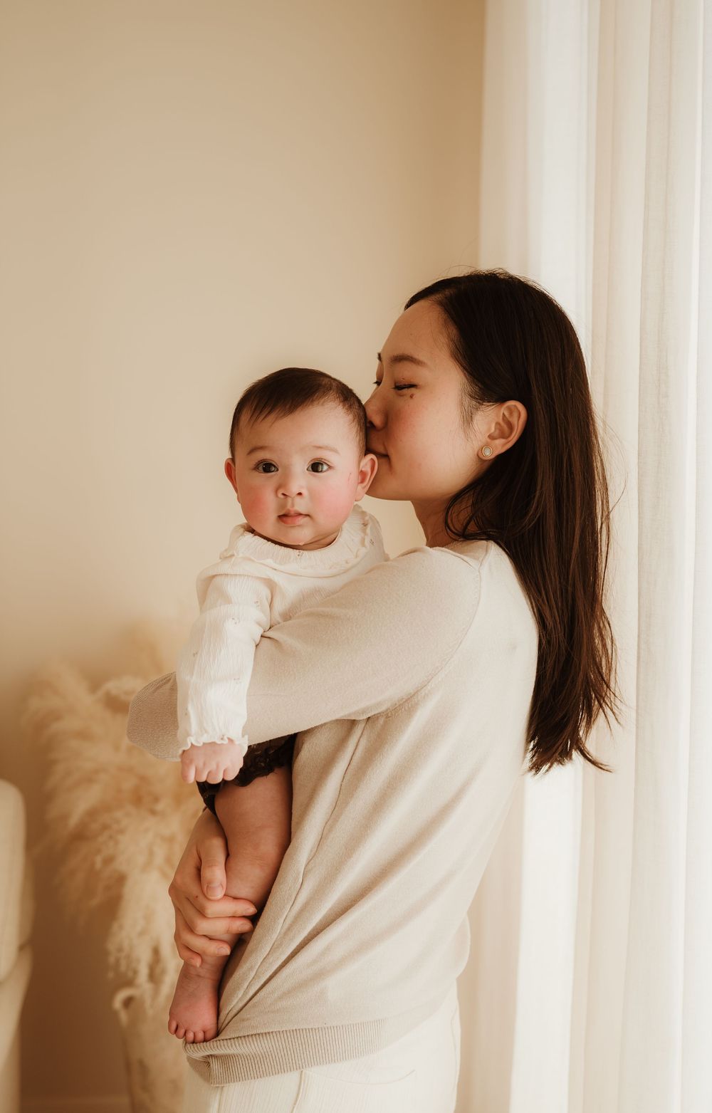 A tender moment shared between parent and baby standing together in soft natural light.