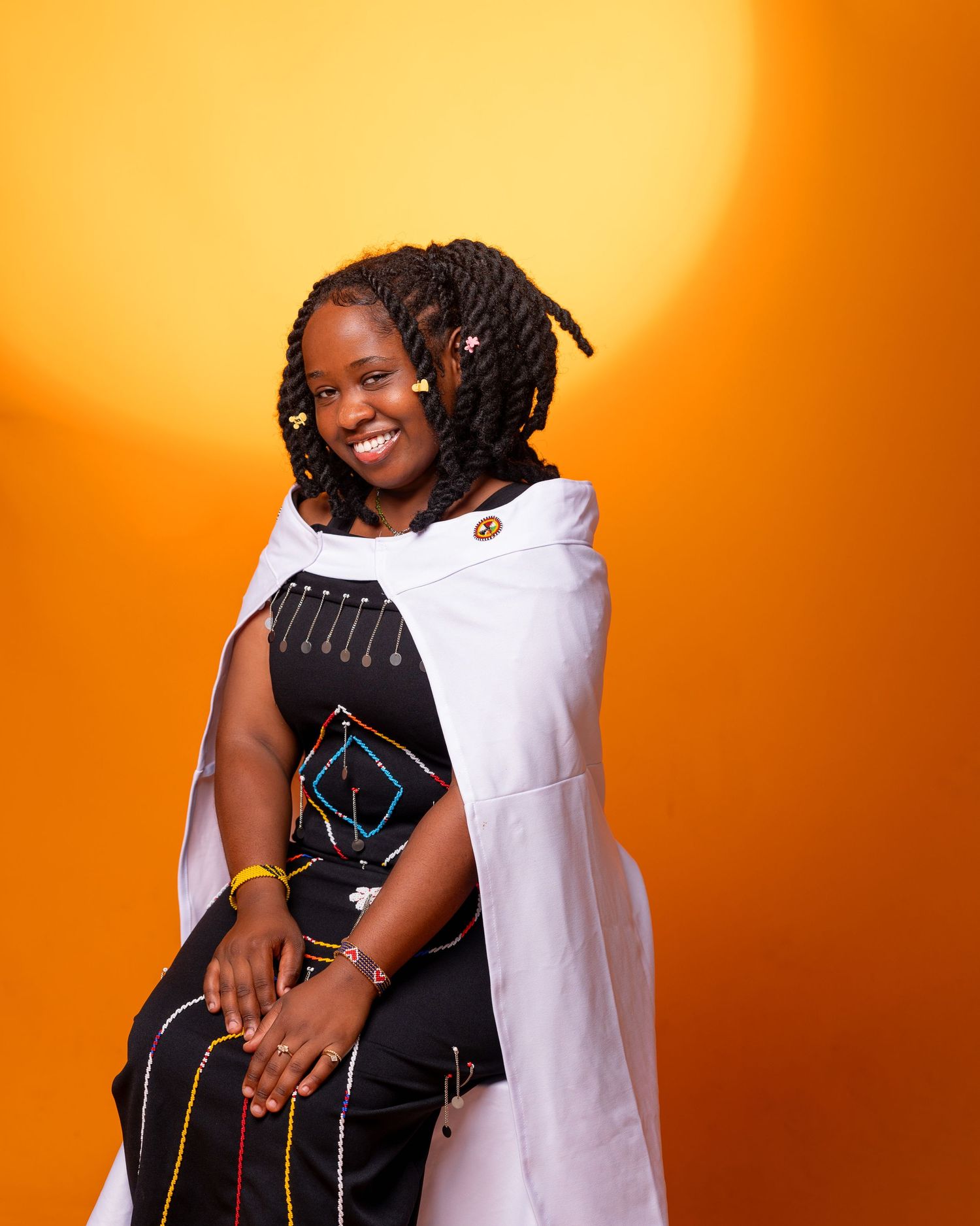 A lady seated while smiling and wears maasai attires