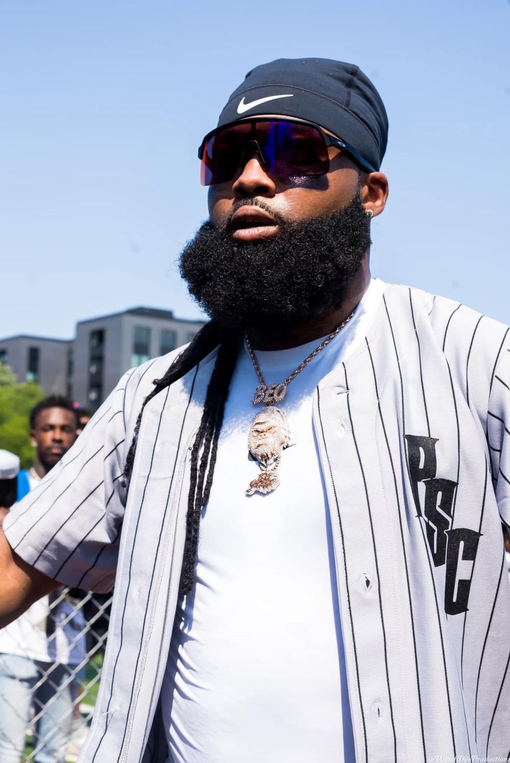Person wearing pinstriped baseball jersey and sunglasses on a sunny day.