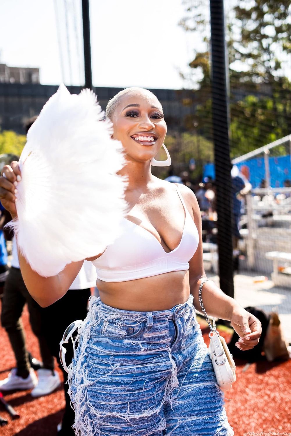 Two people in distressed denim jeans posing with cotton candy outdoors.