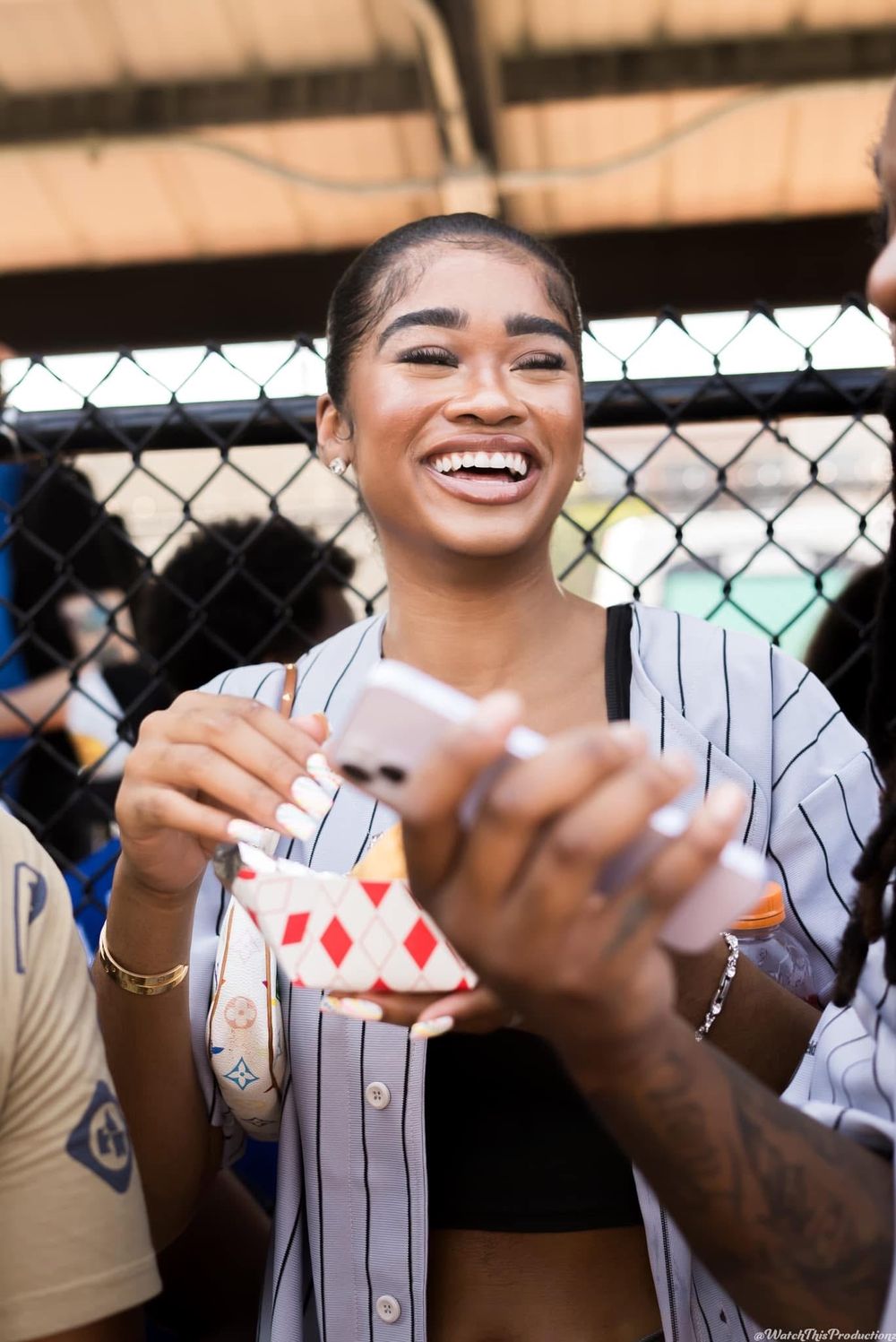 Close-up of hands holding playing cards near a chain-link fence.