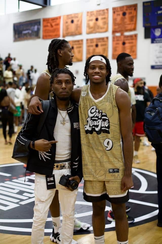 Athletes wearing numbered jerseys posing together on indoor basketball court.