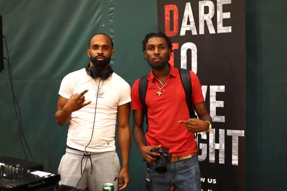 Two people posing in front of 'Dare to Fight' promotional backdrop.
