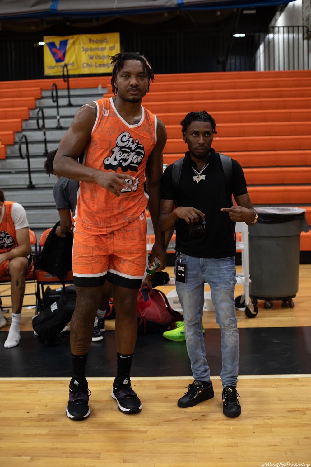 Basketball player in orange uniform standing on gymnasium court.