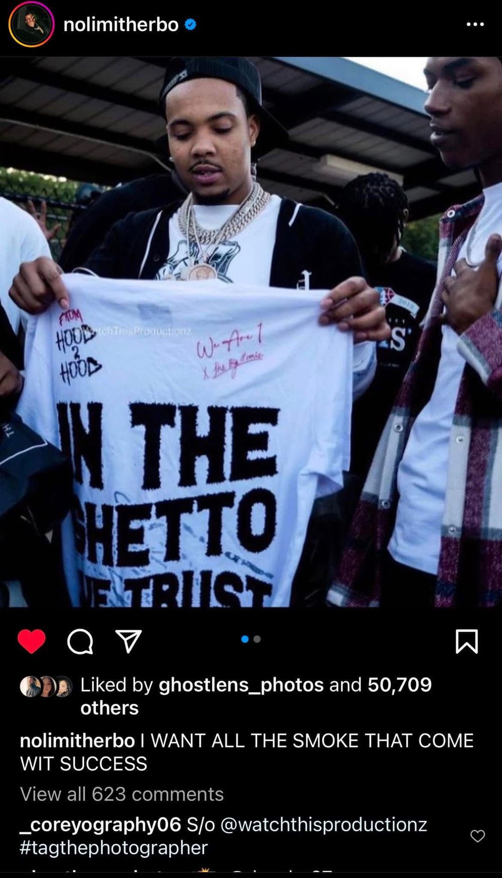 People displaying white t-shirt with text graphics at promotional event.